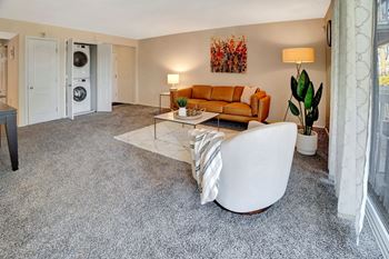A living room with a couch coffee table and a washer and dryer